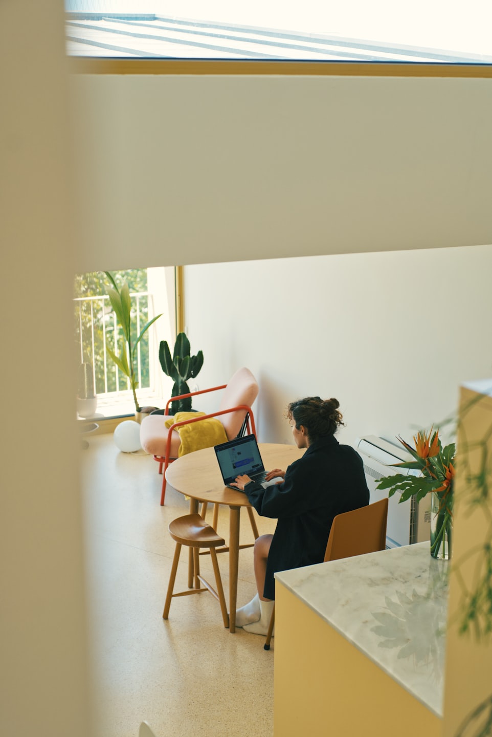 Person working on a laptop at a round wooden table.